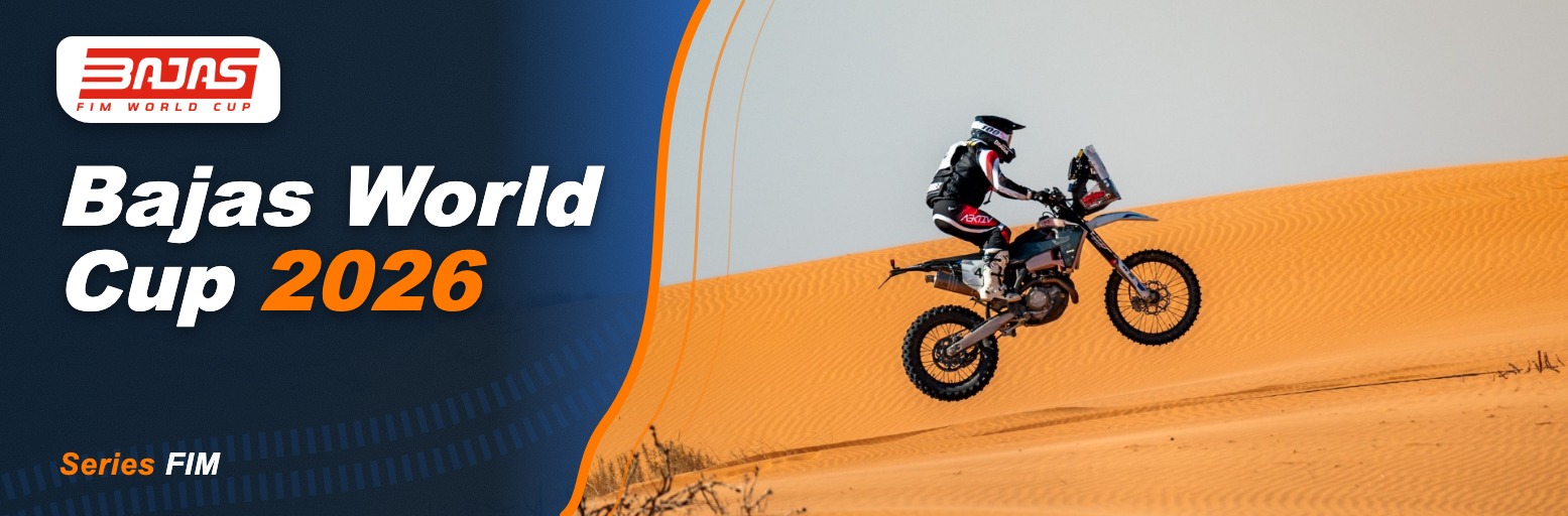 Rally motorcyclist on a sand dune in front of rock formations in the desert