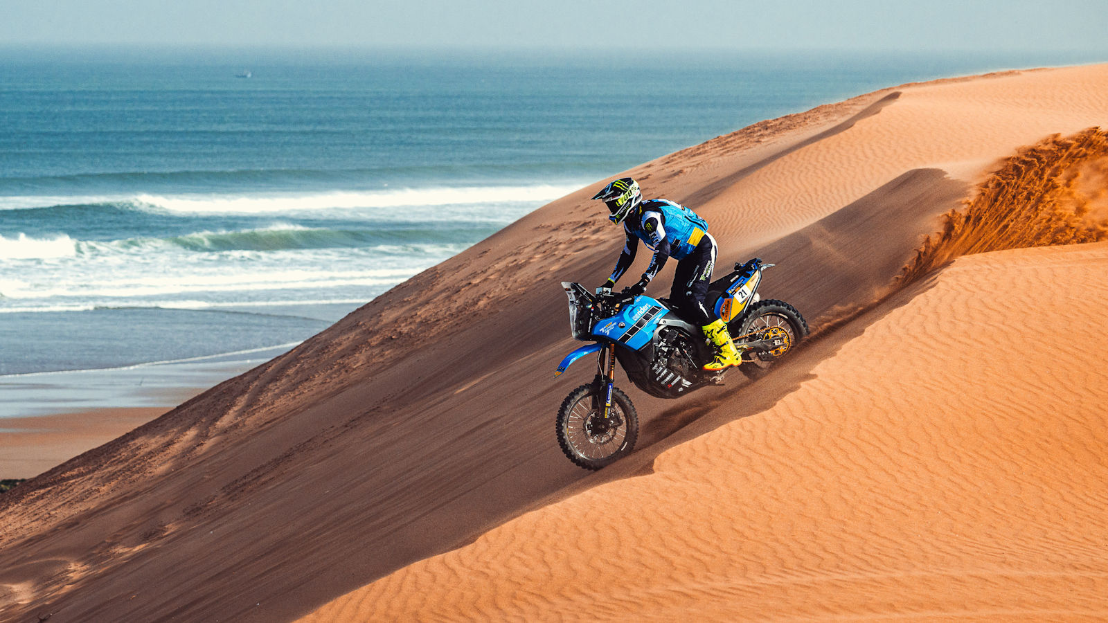 Rally rider on a blue Yamaha descending a sand dune on the Atlantic coast